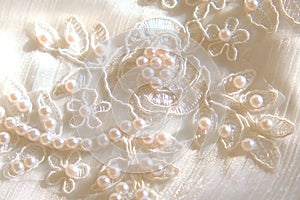 Close up of white wedding dress lace and fabric with beads and pearls