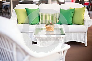 close-up of white wicker patio furniture with green cushions