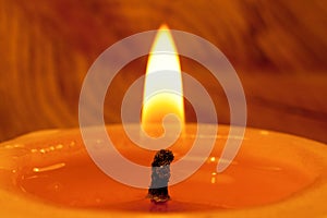 Close-up of wick and flame of burning candle on light backgroun