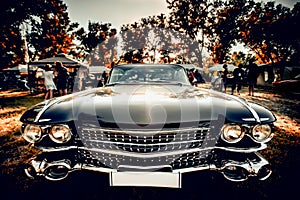 Close-up wide-angled photo of black vintage retro car with shining chrome radiator grille, bumper and headlamps