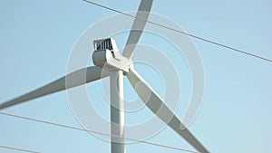 Close up of wind turbine spinning on blue sky background.