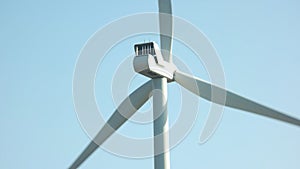 Close up of wind turbine spinning on blue sky background.