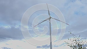 Close-up windmill turning producing energy outdoors. Closeup wind turbine spinning at background of cloudy sky.