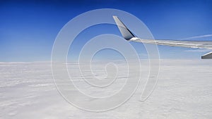 Close up of window with airplane wing. Beautiful cloudscape with clear blue sky