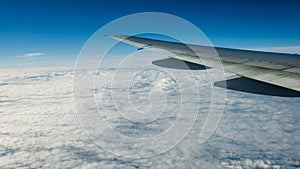 Close up of window with airplane wing. Beautiful cloudscape with clear blue sky