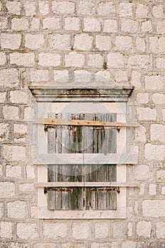 Close-up of a window with closed shutters and hammered boards.
