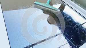 Close-up, in the window glass is reflected a man, worker of cleaning service, in blue overalls and in a cap, blaser