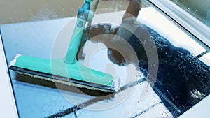 close-up, in the window glass is reflected a man, worker of cleaning service, in blue overalls and in a cap, blaser