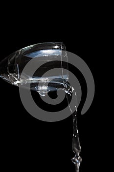 Close up wine glass pouring water, isolated on black background