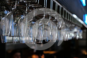 Close up wine glass on rack above counter bar.