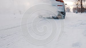 Close up on the winter tires of a moving car. Frozen vehicle driving on the snow covered road