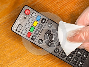 Close-up of wiping clean a TV hand remote control. With an antibacterial fabric tissue. To prevent germs, virus, bacteria and dirt