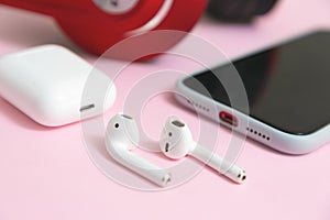 Close-up Wireless earphones, mobile phone and charging case on pink background