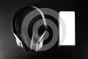 close-up of wireless headphones and.black smartphone with blank screen isolated on white background