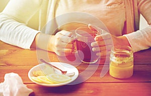 Close up of woman adding lemon to tea cup