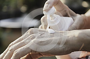 Close up woman applying cream on her hands to moisturize the skin