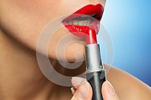 Close up of woman applying red lipstick to lips