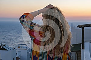 Close up of woman from back enjoying sunset and sea view from terrace of luxury holiday villa