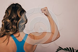 Close up of woman back with flexing her muscles. Female bodybuilder with perfect biceps