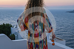 Close up of woman from back looking at sunset and sea view from terrace of luxury holiday villa