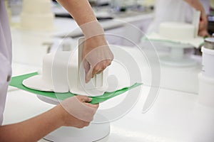 Close Up Of Woman In Bakery Decorating Cake With Royal Icing