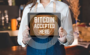 Close up woman barista holding tablet and show bitcoin accepted