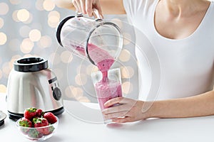 Close up of woman with blender pouring milk shake