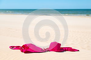 Close up of woman bra at nude beach. Concept of sunbathing naked on the sandy ocean beach. Naturalist lifestyle. Nobody