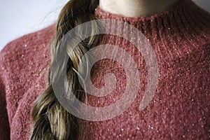 Close-up woman with braid wearing a pink warm soft glitter winter sweater