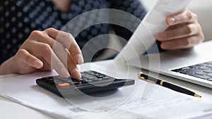 Close up woman calculating finances, using calculator and laptop