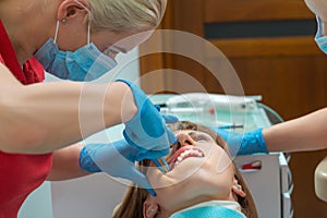 Close-up woman with ceramic braces on teeth at the dental office. Dentist holding dental tool - corner ligature cutters. Orthodont