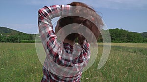 Close-up of woman in checkered shirt holding her hair with hands outdoor from back view