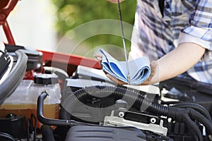 Close-Up Of Woman Checking Car Engine Oil Level On Dipstick