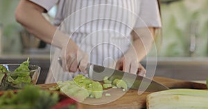 Close up of a woman chopping vegetables in a kitchen