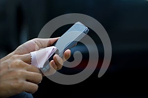 Close up of a woman cleaning mobile smart phone with fabric in dark background