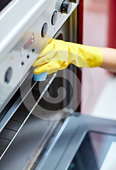 Close up of woman cleaning oven at home kitchen