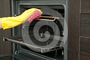 Close up of woman cleaning oven at home kitchen