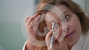 Close-up. A woman clumsily draws her eyebrows with an eyebrow pencil.