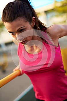 Close up of woman concentrating while doing tricep dips.