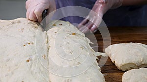 Close up for woman in cooking gloves cutting the dough into pieces with a special knife. Stock footage. Women hands cut