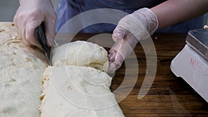 Close up for woman in cooking gloves cutting the dough into pieces with a special knife. Stock footage. Women hands cut