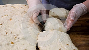 Close up for woman in cooking gloves cutting the dough into pieces with a special knife. Stock footage. Women hands cut