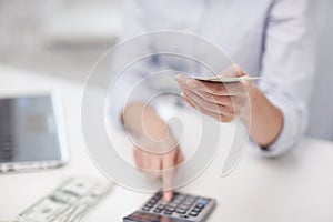 Close up of woman counting money with calculator