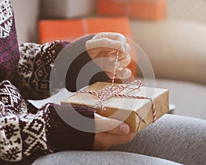 Close up of woman in creative sweater unwrapping presents