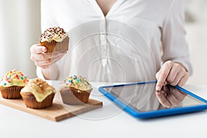 Close up of woman with cupcakes and tablet pc