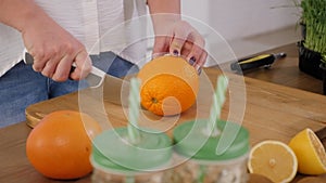Close-up of a woman cutting oranges on a wooden cutting board.