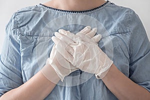 Close-up woman doctor hands in white medical rubber gloves on heart blue coat background. Stop virus and coronovirus