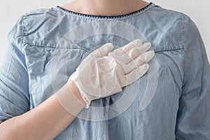 Close-up woman doctor hands in white medical rubber gloves on heart blue coat background. Stop virus and coronovirus