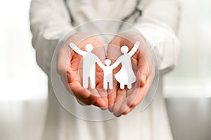 Close up of woman doctor in white uniform with stethoscope holding paper family cutout icon, foster care, homeless support,