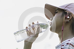Close up of a woman drinking water from a bottle after exercise. Portrait of a woman drinking a water at outside